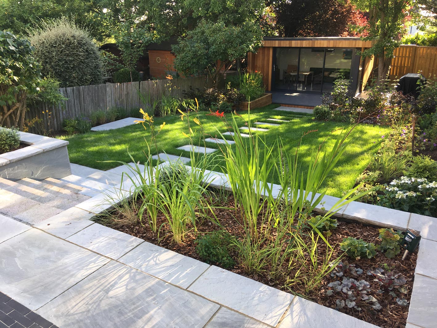 Sleeper raised beds full of planting and a beech hedging help to create an area in the garden to retreat to.