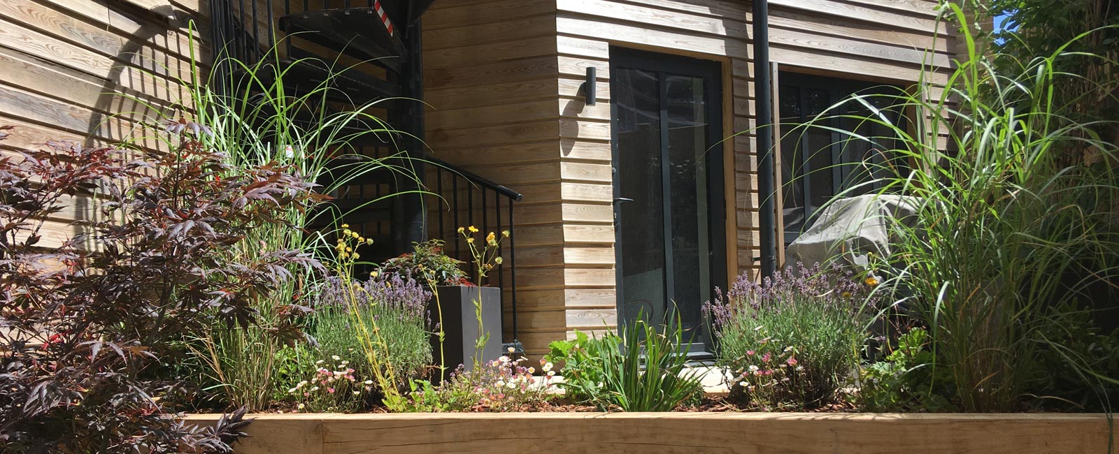 The redesign features a raised deck, oak sleeper beds, privacy screening and even a cantilevered roof structure with seating below.