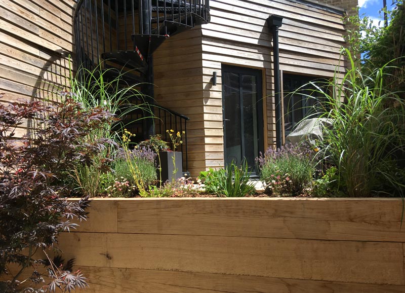 The redesign features a raised deck, oak sleeper beds, privacy screening and even a cantilevered roof structure with seating below.