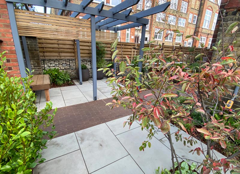 To create privacy, we designed and constructed a grey stained pergola structure that also extended across the entrance path.