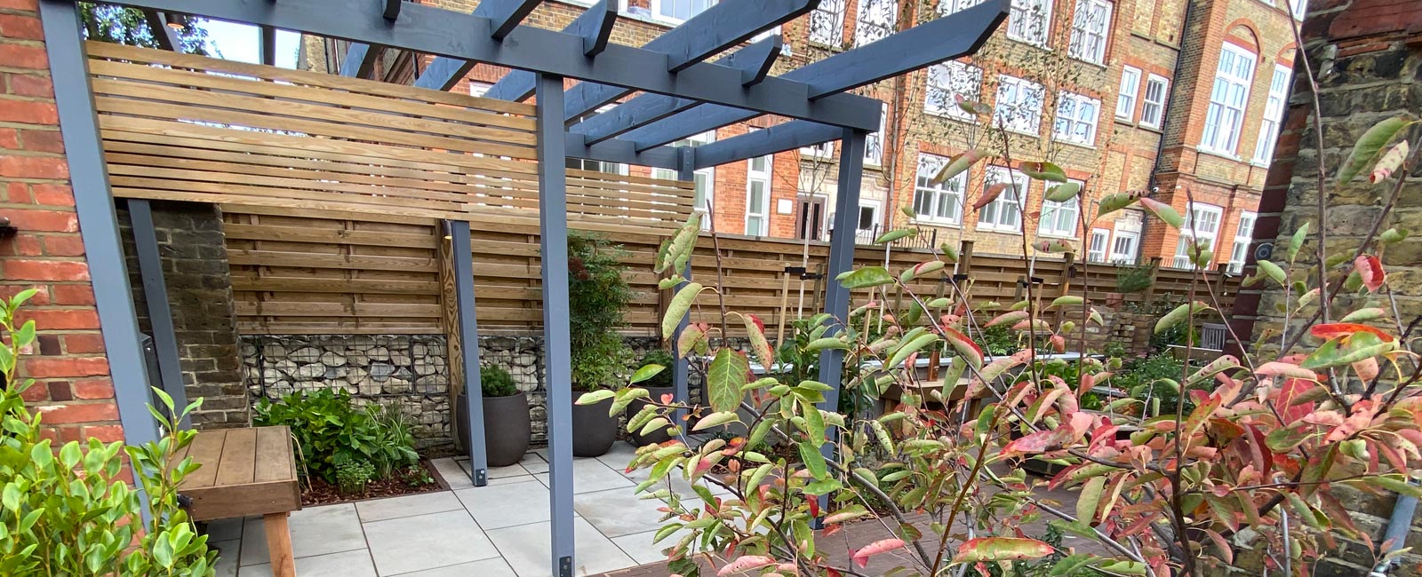 To create privacy, we designed and constructed a grey stained pergola structure that also extended across the entrance path.