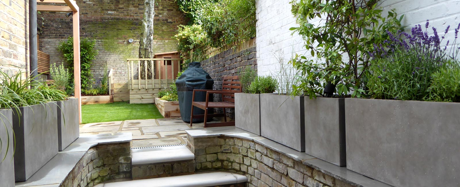 Bullnosed steps, an off-white wall and terrazzo planters containing shade-tolerant plants make for a grand entrance from the lower terrace.