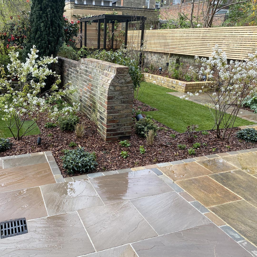 A close up of the focal multi-stem Amelanchier trees in bloom and the original Victorian wall that once divided the two gardens.