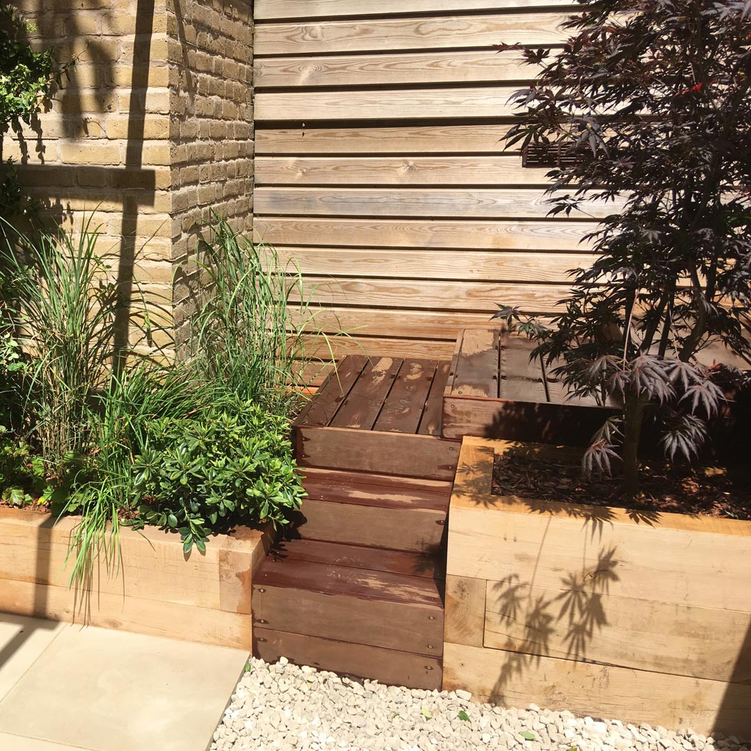 The red tones of the Acer palmatum tree balance with the warm colours of the hardwood steps.