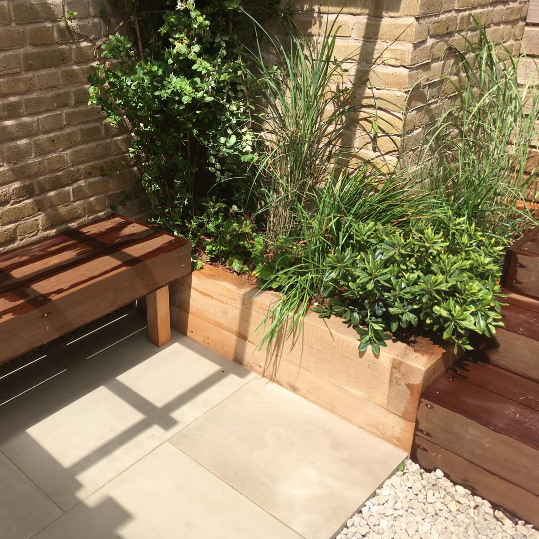 Low maintenance planting; Pittosporum tobira ’Nanum’, Miscanthus, Luzula and Lonicera in a bespoke Oak sleeper raised bed.