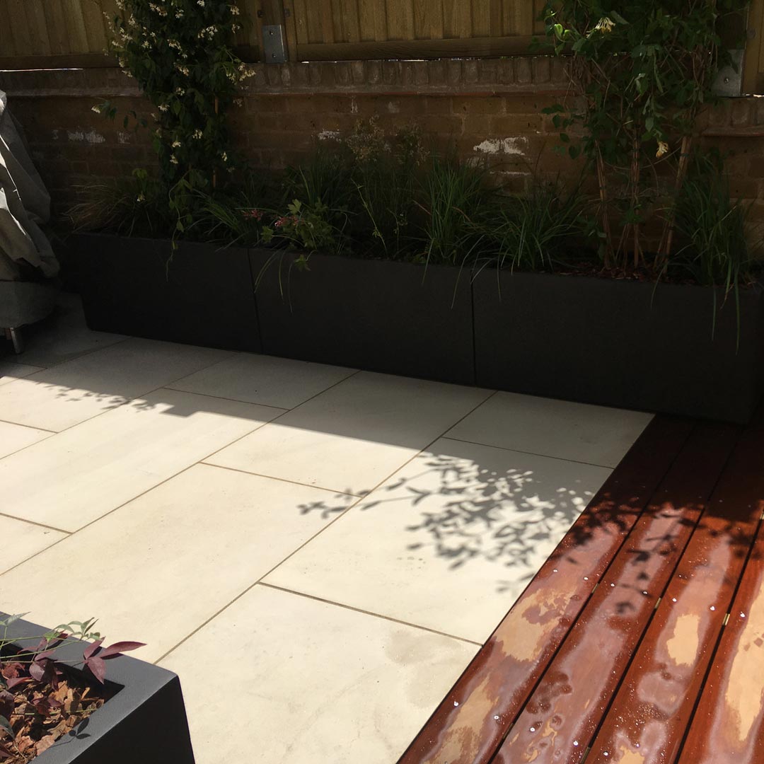 The area of the upper terrace has been extended forward with hardwood decking and the concrete paving has been replaced with light sandstone. Space saving fibreglass planters bring much needed greenery.