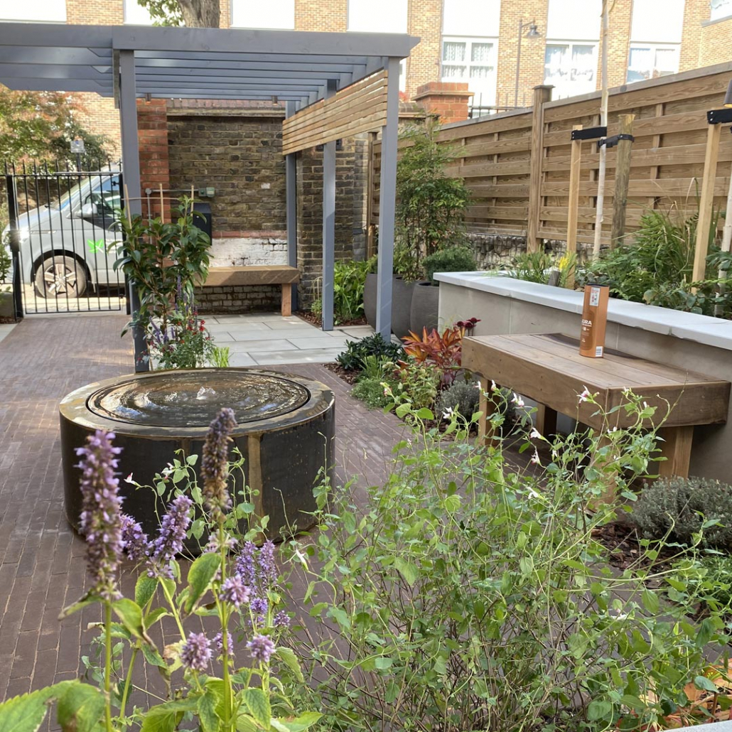 A painted softwood pergola, circular water table, stylish clay pavers and raised beds.