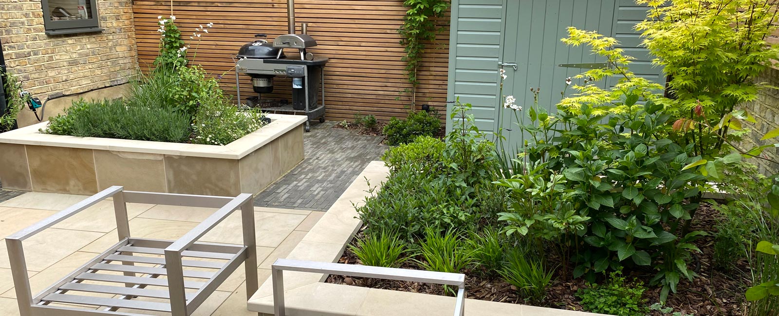 Various zones are divided by raised beds, softened with stunning Mediterranean planting and also feature larch screening & outdoor lighting.