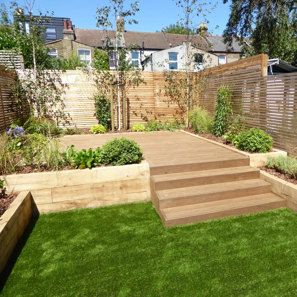 Raised, retaining oak sleeper beds and evergreen, low-maintenance planting frame the raised sundeck.