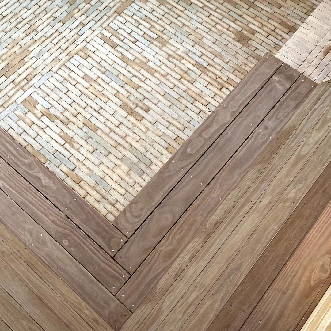 Detail of the bespoke L-shaped Kebony bench designed to make the most of limited space. Clay paver bricks laid in an alternating stretcher bond pattern.