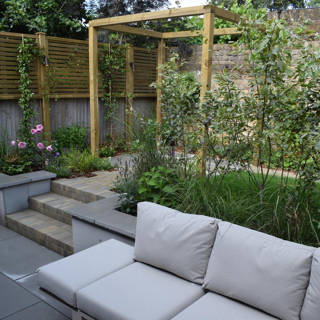 The sofa fits snuggly in the corner to a backdrop of multi-stem Amelanchier trees.