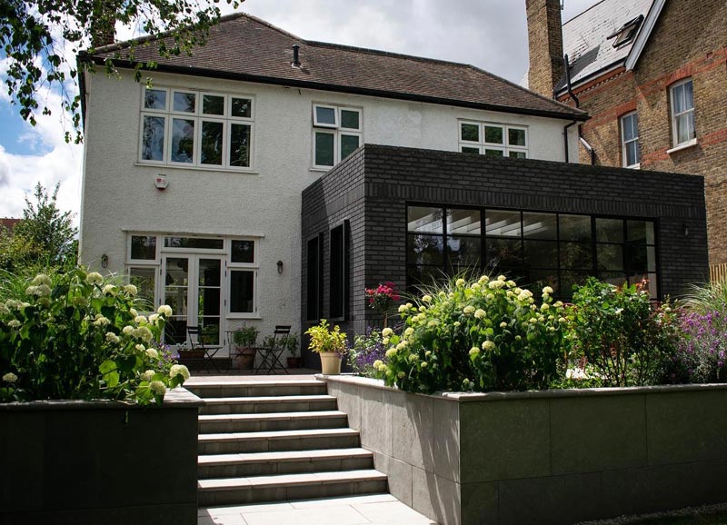 Here you can see the side terrace to the left of the new extension, new steps, raised flower beds, and the herbaceous planting in an English style with some Mediterranean influences.