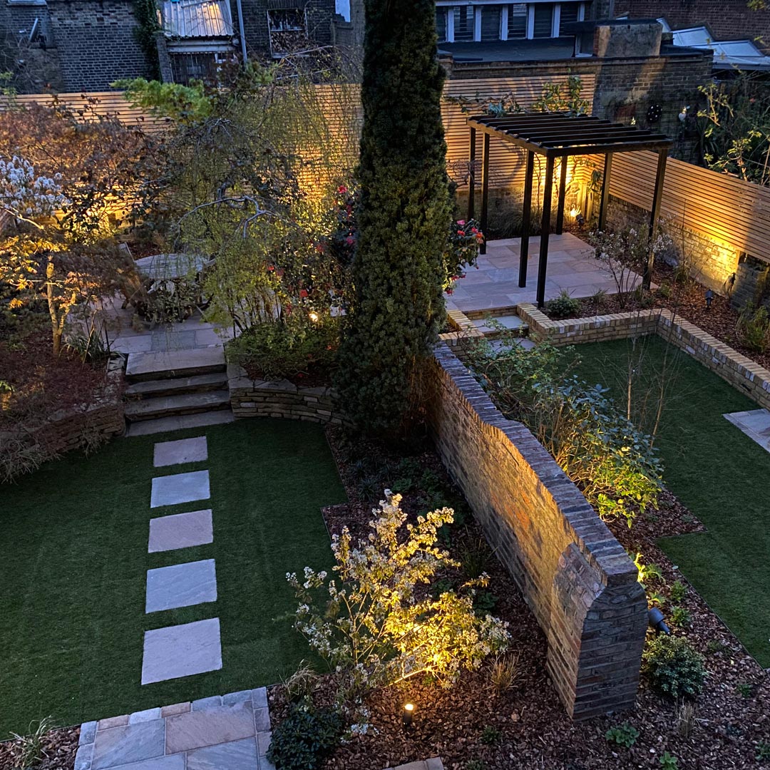 A view at night from above shows both the gardens lit up by the clever placement of outdoor lighting.
