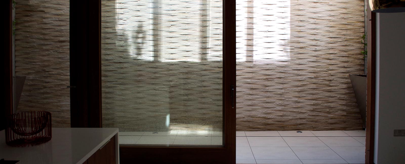 The modern design for the light well features quartz stone cladding, bespoke stainless steel planters with climbing plants and low maintenance grasses to the top.