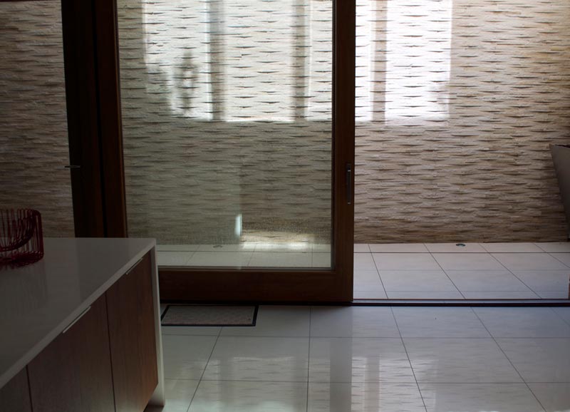 The modern design for the light well features quartz stone cladding, bespoke stainless steel planters with climbing plants and low maintenance grasses to the top.