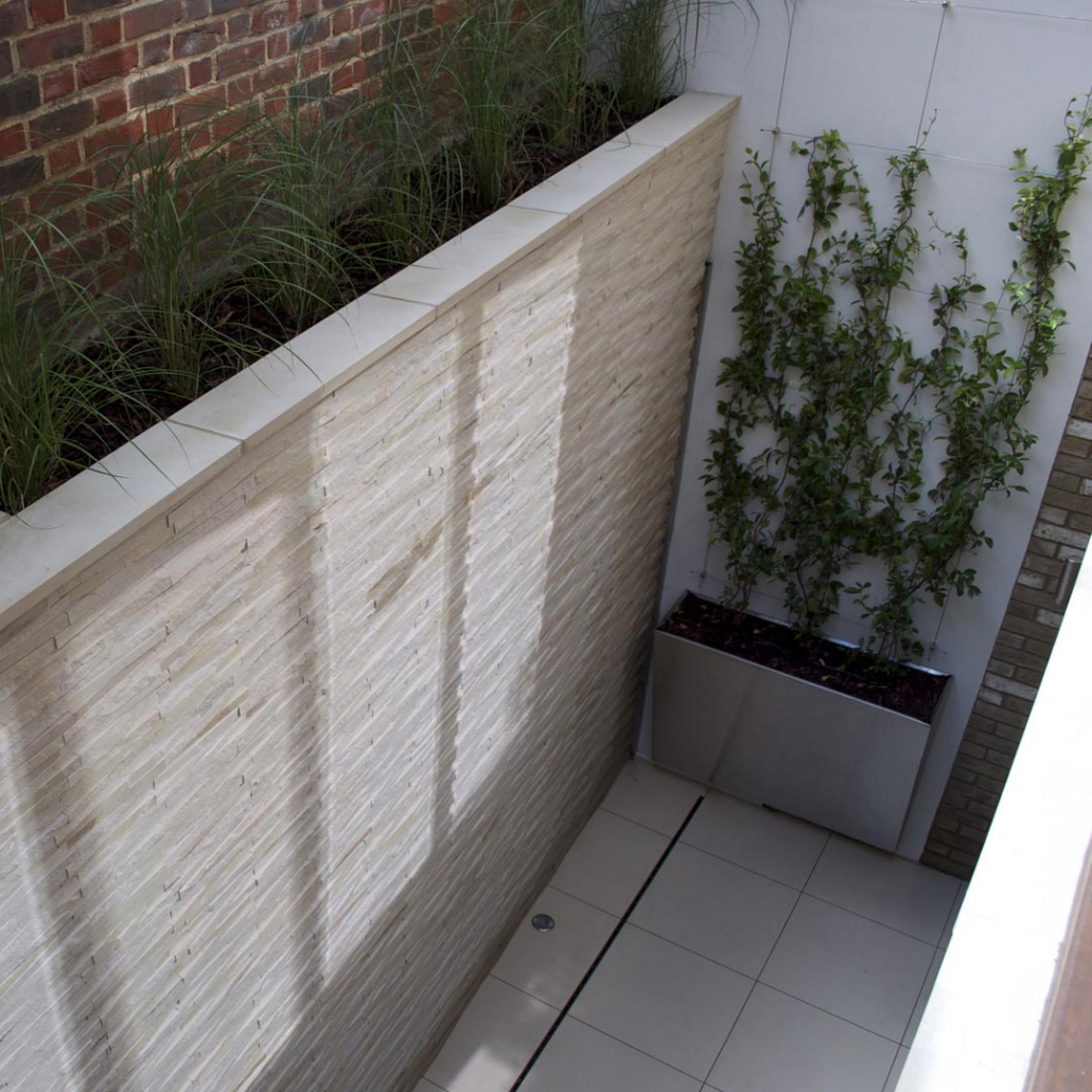View from above of the light well in WC1 of a buff quartz stone clad wall.