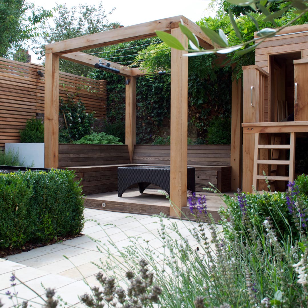 Garden pergola with stainless steel cables for growing Wisteria across, integral benches and rendered raised beds.
