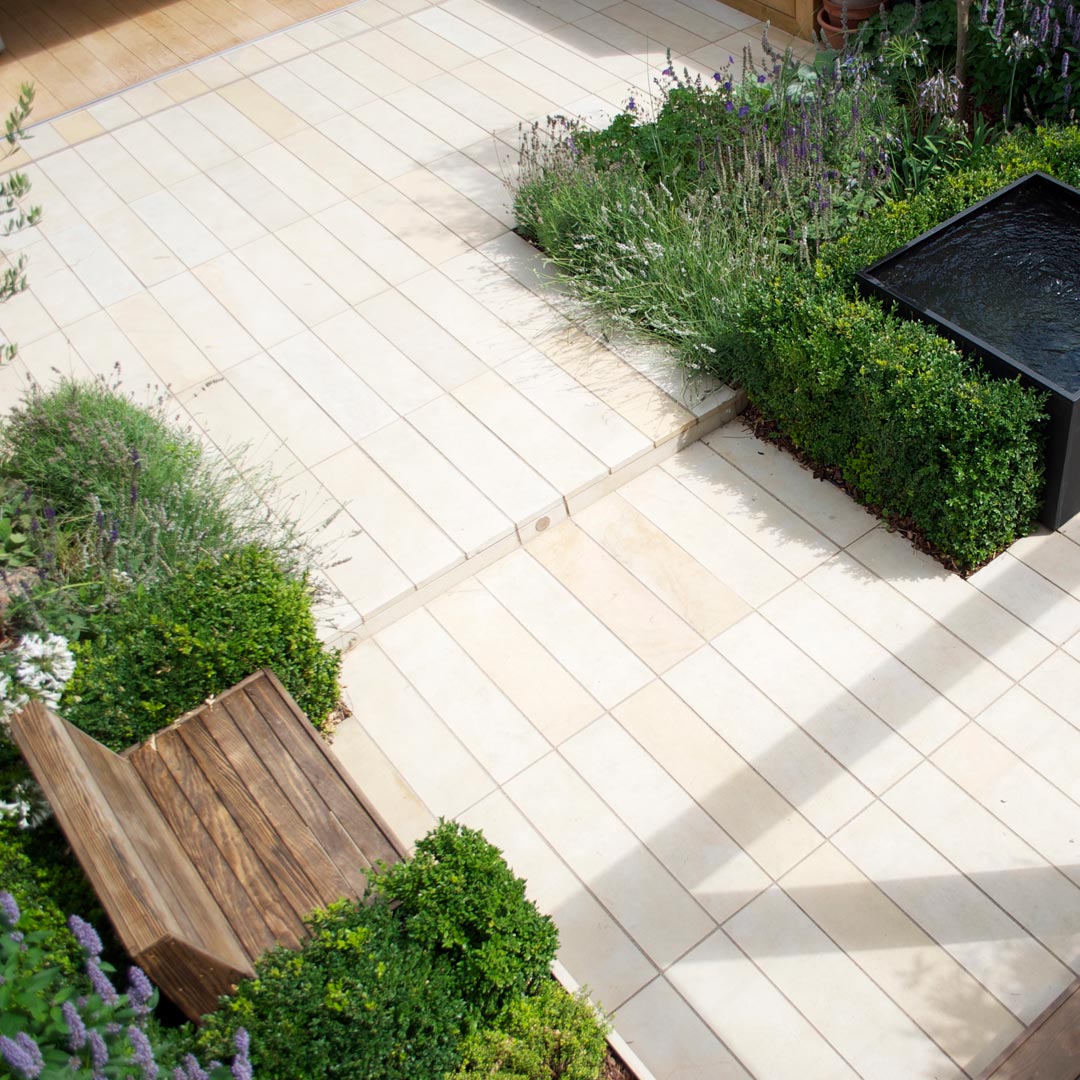 Looking down on to the garden from above shows the sawn sandstone plank paving connecting to the narrow planks of timber floor of the house interior.