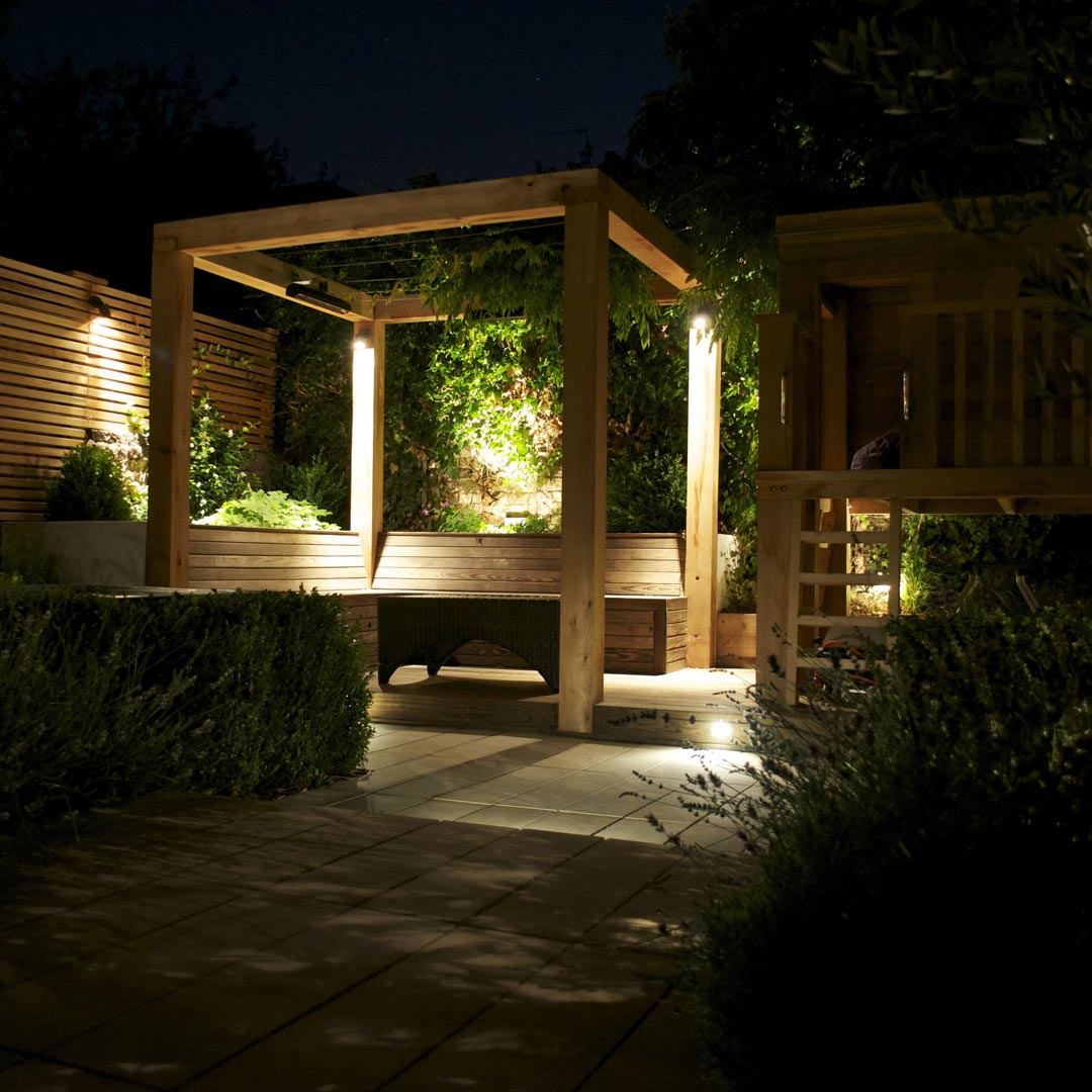Pergola cube at night, subtly lit with corner lighting. A low-voltage overhead heater has been installed for the colder evenings.