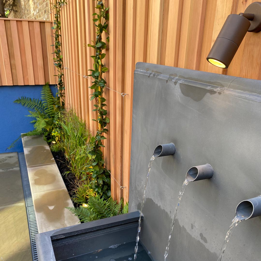 City noise pollution is filtered by the gentle sound of trickling water. Trachelospermum climb onto steel cables to create a green wall.